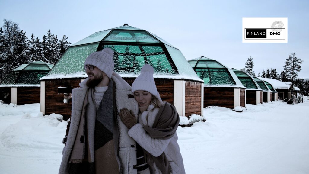 Rebecca and Stanley standing in front of igloos at a resort in Finnish Lapland during their Finland tour from Australia.